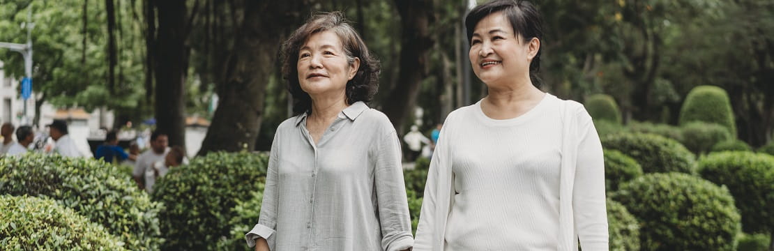 Elderly couple holds hands and walks through a garden